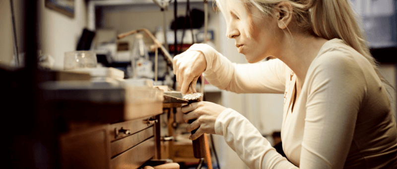 Female bench jeweller using a file on a jewellery item